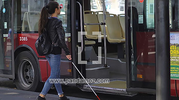 عکس یک زن جوان نابینا در حال سوار شدن به اتوبوس. در تصویر دختر عصای سفید مخصوص نابینایان در دست دارد و کوله پشتی بر پشت خود دارد