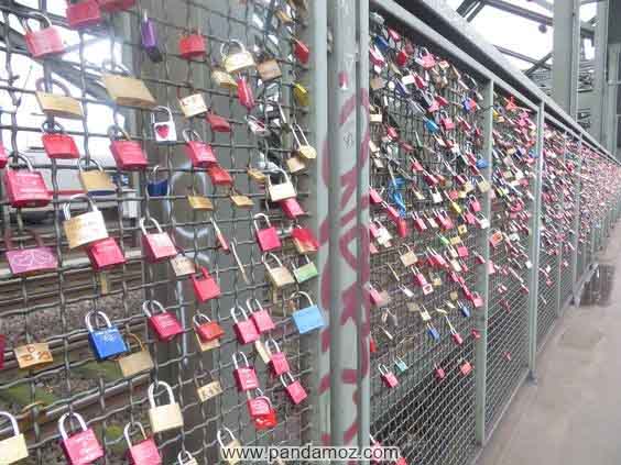 عکس از قفل های رنگارنگ و مختلف بر روی دیوار توری که به عنوان قفل عشق از طرف مردم و زوج های عاشقان روی آنها بسته و قفل شده